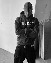 a man wearing a hoodie with the word reject on it